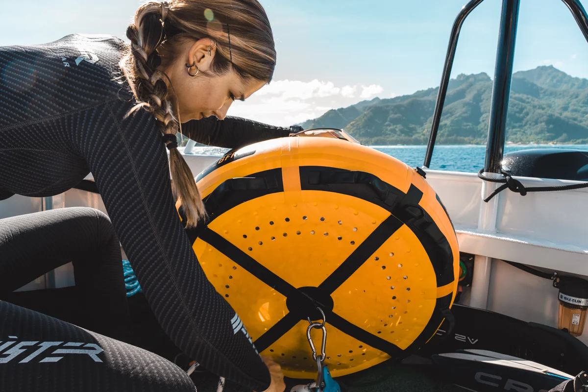 Marie, de profil, soulevant une bouée d’apnée sur le bateau